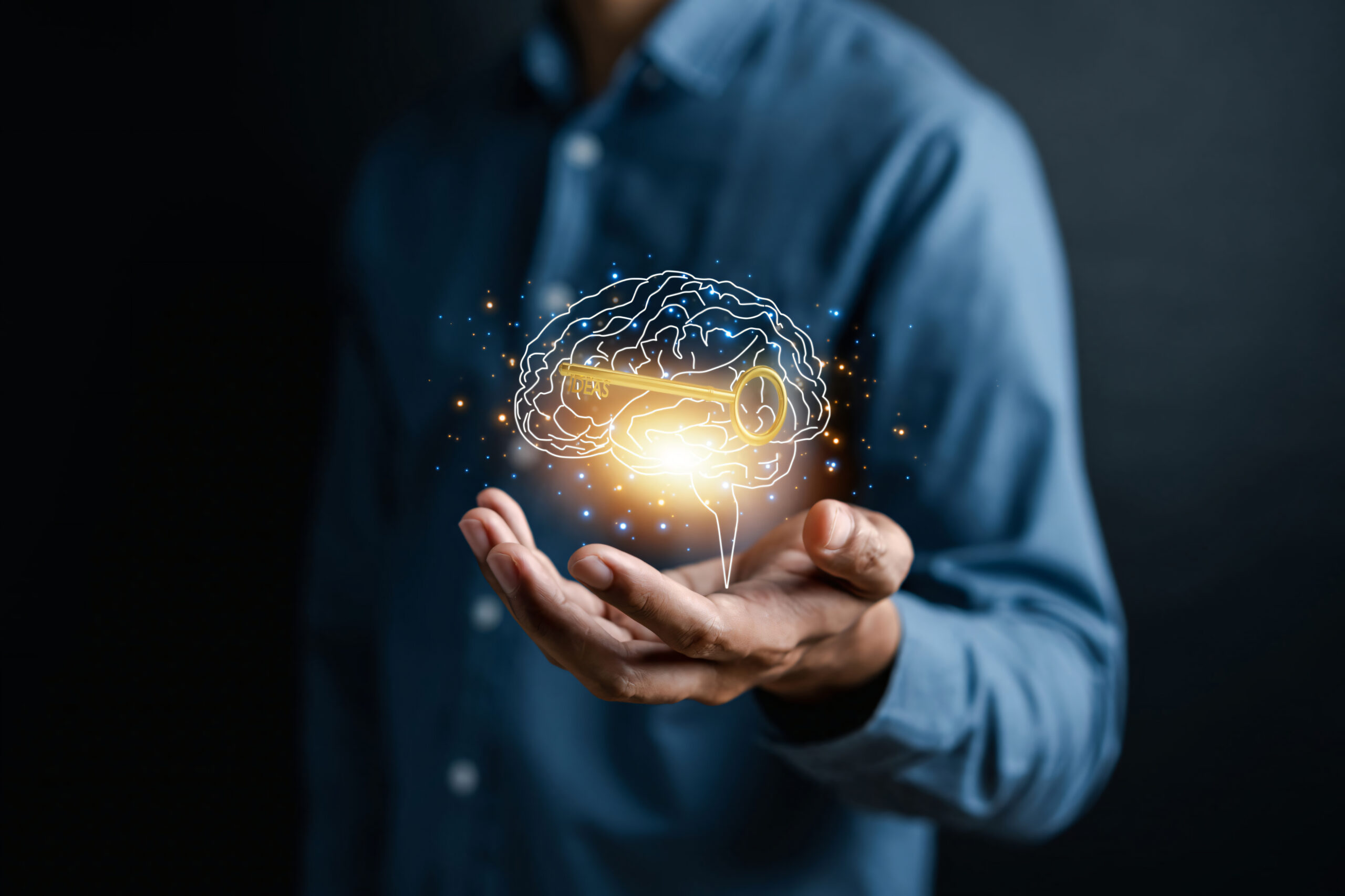 Hand holding virtual human brain and golden key icon, idea creative intelligence to success business goal concept